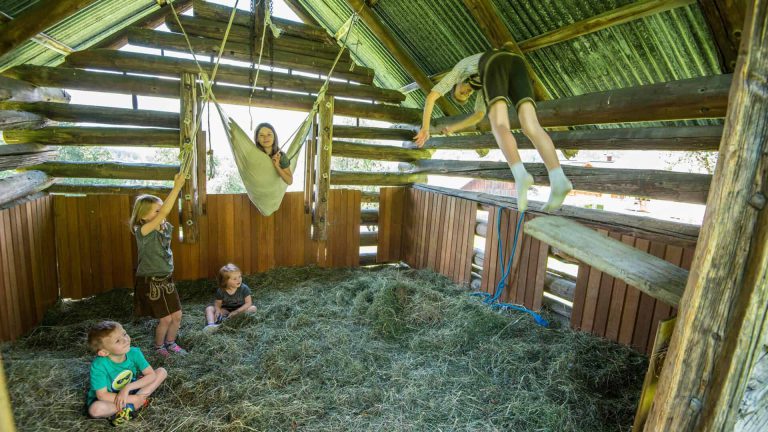 Kinder spielen und klettern im Heu auf einem Bauernhof in St. Johann im Pongau.