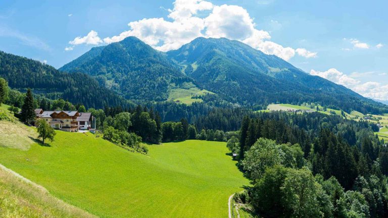 Blick auf den Maurachhof in St. Johann im Pongau, umgeben von grünen Wiesen und Bergen.