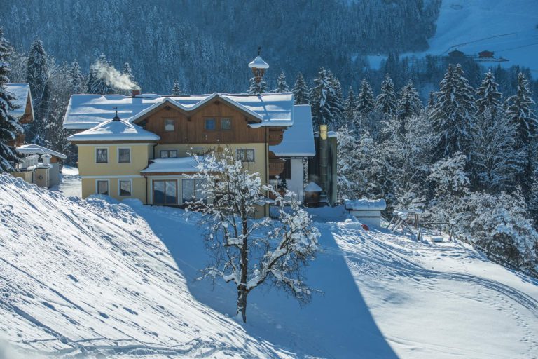 Winter view of the Maurachhof in St. Johann im Pongau, surrounded by snow-covered trees.